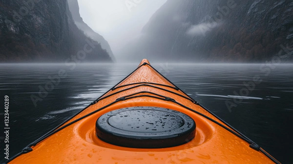 Obraz Exploring a Serene Lake in a Vibrant Orange Kayak Surrounded by Misty Mountains on a Cloudy Day
