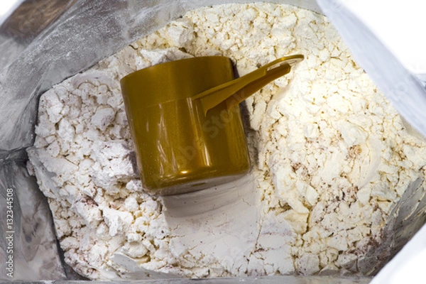 Obraz Bag and heap of vanilla chocolate whey protein. Nutrition for fitness and bodybuilding for gaining muscles. Full brown scoop inside. white background.