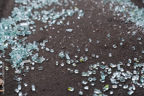 Fototapeta This image effectively showcases a variety of shattered glass fragments scattered across dark pavement, highlighting the urban debris and potential dangers that they pose to unsuspecting pedestrians