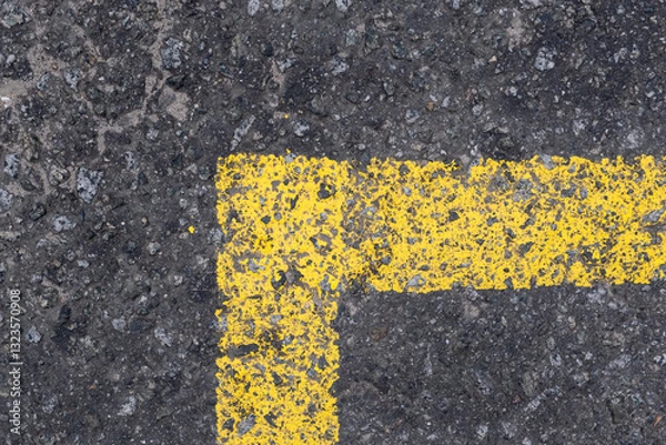 Fototapeta This closeup shows a weathered yellow parking line on textured asphalt, highlighting the contrast between the vibrant paint and the rough pavement, creating a visually appealing detail