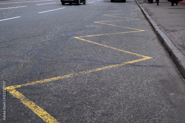 Fototapeta This closeup shows a zigzag pattern of bright yellow lines on a busy city street, highlighting important traffic markings that guide vehicles and supporting urban movement in the bustling metropolis