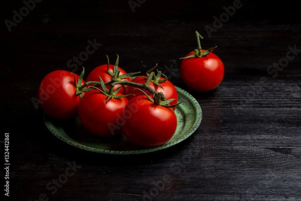 Fototapeta Top view of tomatoes on green plate on dark table, horizontal with copy space