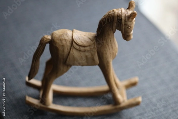 Fototapeta A classic wooden rocking horse sits on a bright blue surface, ready for imagination and play.