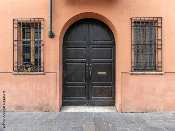 Obraz A vintage, arched, wooden door and two windows on an ocher colored wall by the sidewalk. Travel in Italy.