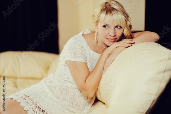 Fototapeta Молодая женщина со светлыми короткими волосами сидит на диване