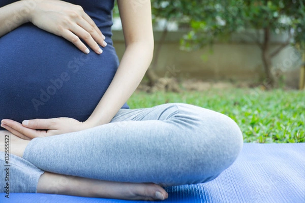 Obraz Close up of pregnant woman yoga  in garden