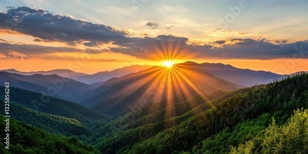 Obraz A breathtaking sunrise over rolling mountains, casting golden rays through the clouds, creating a serene and peaceful landscape.