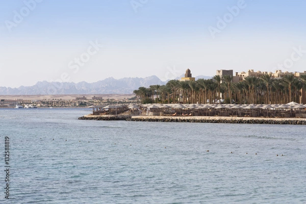 Fototapeta An oasis of palm trees and greenery photo. Embankment along the beach in Makadi, Egypt