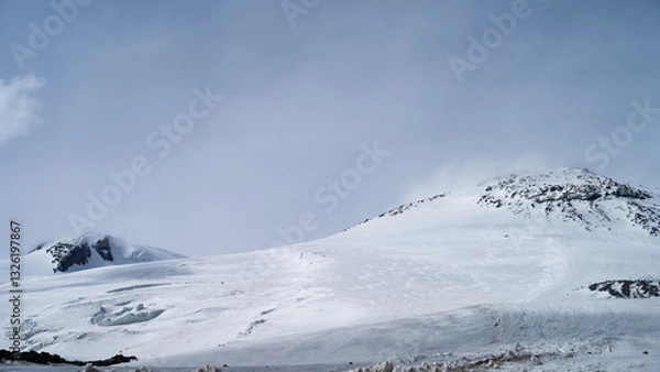Fototapeta snowy mountain peaks in the clouds