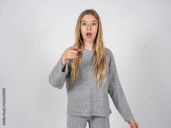 Fototapeta Shocked beautiful caucasian girl wearing grey track-suit points at you with stunned expression