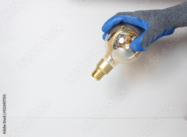 Obraz light bulb in hand in blue glove