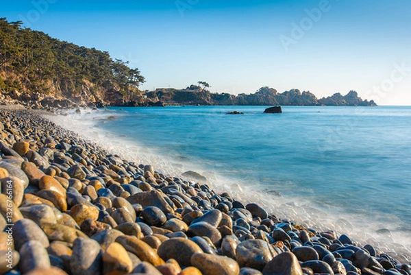 Fototapeta Beach in Korea with round rocks and a long exposure water  tide at sunrise