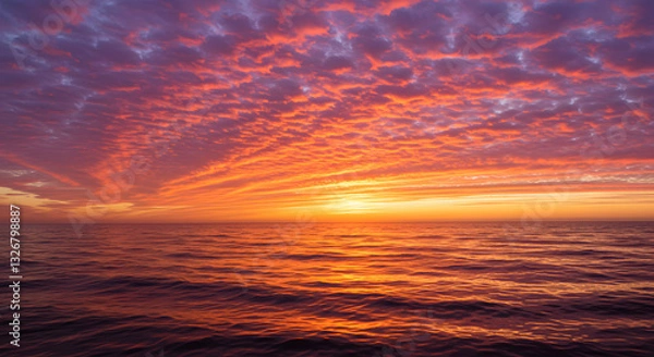 Obraz A stunning sunset over the ocean, with warm orange and pink hues reflecting on the water.