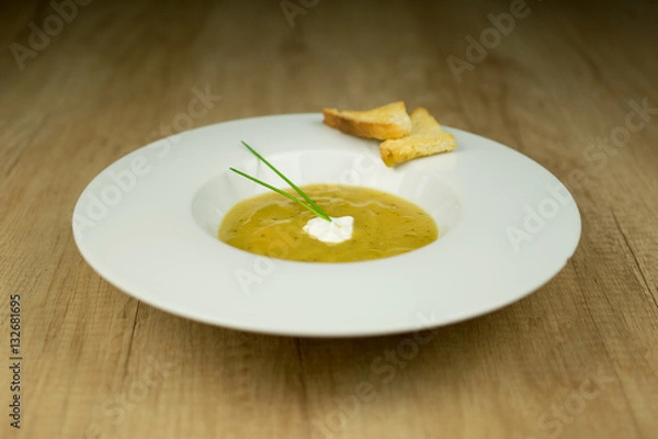 Fototapeta Cream soup with toast on plate on wooden table