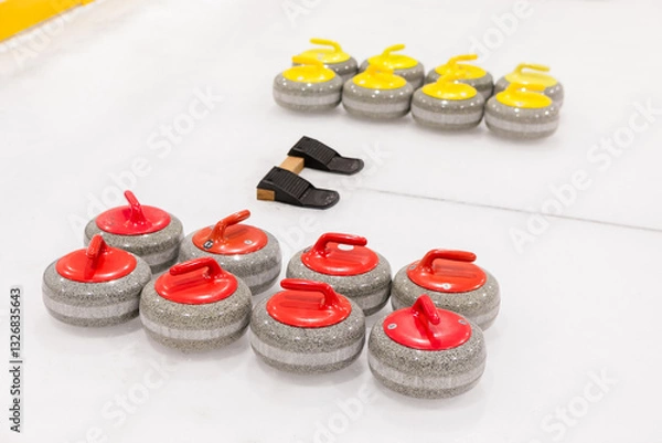 Fototapeta Two sets of curling stones of different colors for two teams, placed near concentric rings on an ice rink