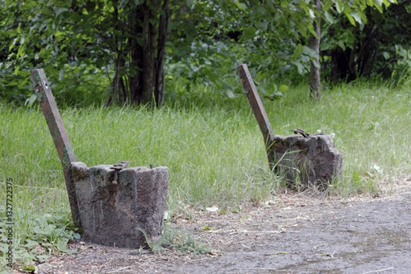 Fototapeta Old aged weathered demolished wooden bench remains, horizontal abandoned public park vintage seat closeup grey textured ruined reinforced concrete legs base green painted rusted iron backrest supports