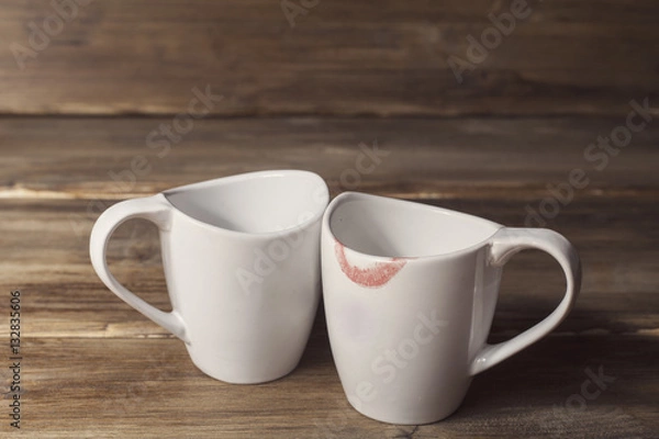 Fototapeta Two white cups, one of them is wearing lipstick, the relationship of men and women, Valentine's day, on the background of old wooden planks
