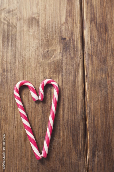 Fototapeta Heart in honor of Valentine's day made from candy cane on a background of old wooden planks