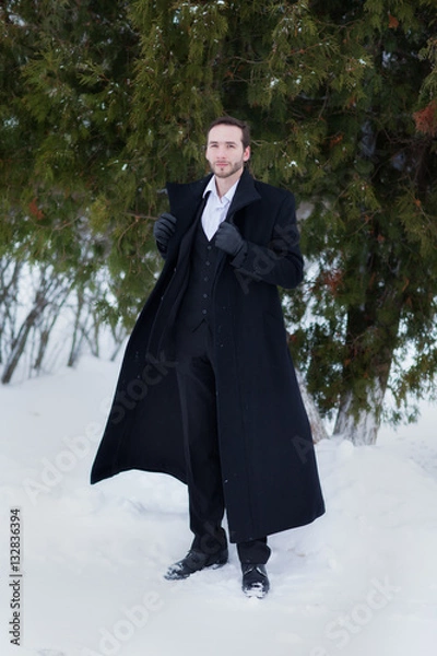 Fototapeta Male businessman sitting on a bench, holding a business briefcase with documents, in the winter on the street