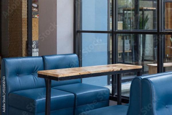 Obraz Pusty drewniany stół i niebieska sofa restauracja