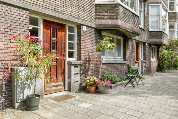 Obraz A welcoming entrance featuring a blend of vibrant plants and a cozy seating area, set within a stylish brick building.