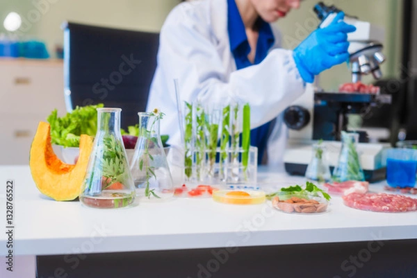 Obraz Middle-aged female laboratory worker wearing blue gloves conducts lab test on food ingredients lettuce, cucumber, pork. Using microscope, she analyzes nutrients, preservatives, food safety records.