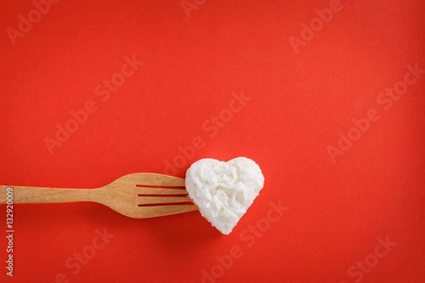 Fototapeta Heart shaped cooked rice with a fork on red background.