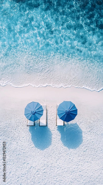 Obraz top down view of two blue umbrellas and beach chairs on white sand by clear turquoise water