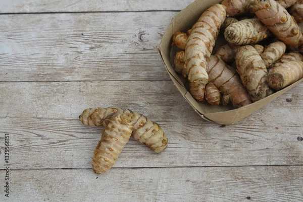 Fototapeta Fresh turmeric roots in cardboard box on rustic wooden table