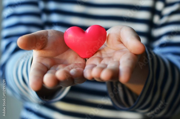 Obraz child holding a small pink heart. symbol of love, family, hope. Backgrounds for cards on Valentine's Day. Backgrounds for social posters about the preservation of the family and children.
