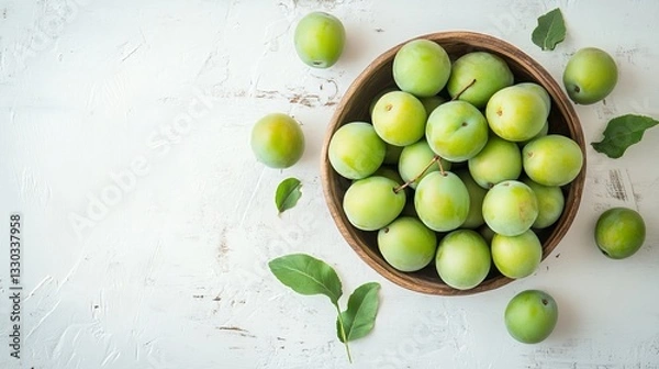 Fototapeta Fresh ripe organic green plums or greengage in bowl on white rustic background, heap of summer fruits concept 