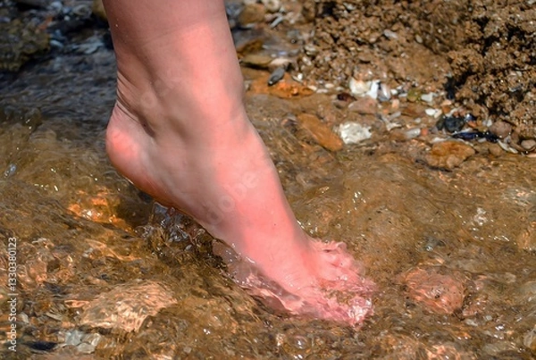 Fototapeta Close-up of a girl's foot stepping into the water