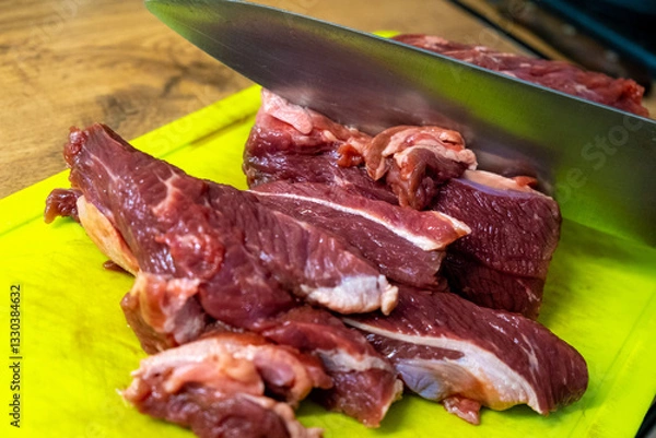 Fototapeta A display of freshly cut meat on a chopping board with a sharp knife nearby, ready to prepare