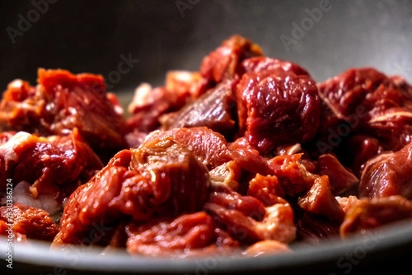 Fototapeta Sizzling Raw Meat Cuts Cooking in a Dark Pan, Ready to Be Barbecued and Eaten Soon