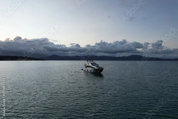 Fototapeta Elegant yacht anchored in calm waters at twilight by the mountains