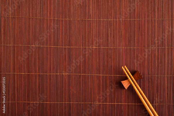 Obraz Two chopsticks on a bamboo mat.