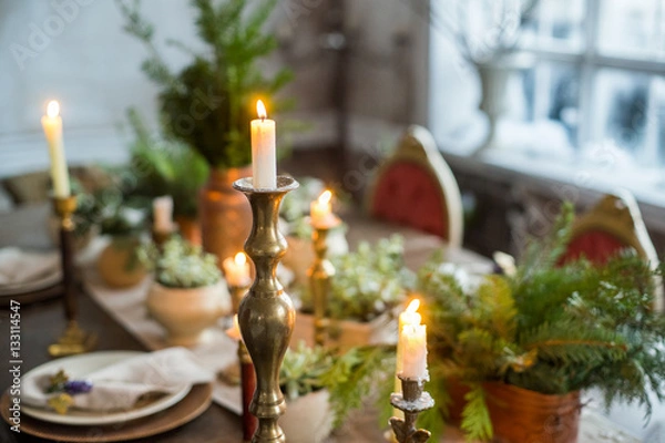 Fototapeta Festive table setting by candlelight, indoor. Winter decoration in rustic style