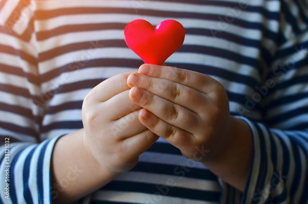Obraz child holding a small pink heart. symbol of love, family, hope. Backgrounds for cards on Valentine's Day. Backgrounds for social posters about the preservation of the family and children.
