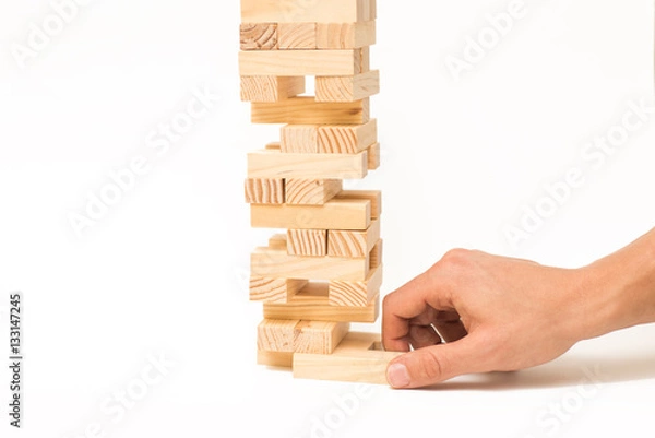 Fototapeta Tower of wooden blocks Jenga game and man's hand