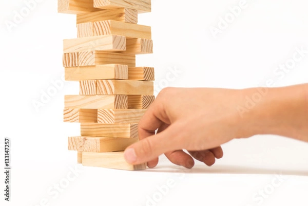 Fototapeta Tower of wooden blocks Jenga game and man's hand