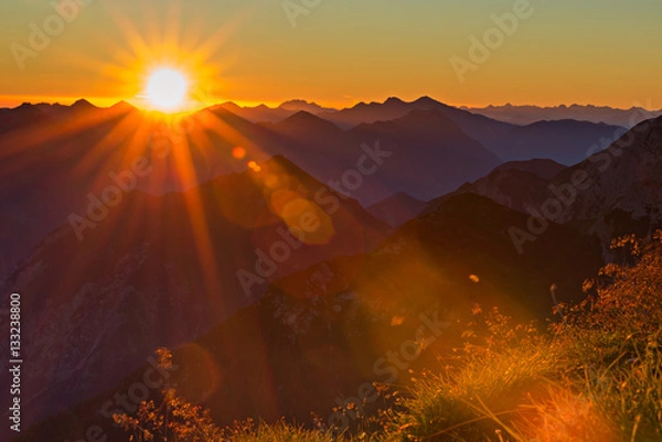 Obraz red orange sunset with sunbeams to grass in tyrol mountains