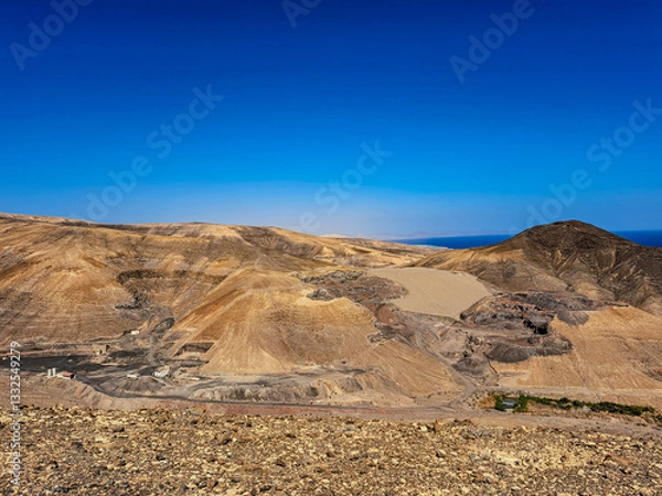 Fototapeta mountainous terrain on Fuerteventura, view from above of the southern coast of the island, volcanic landscape in the distance visible ocean