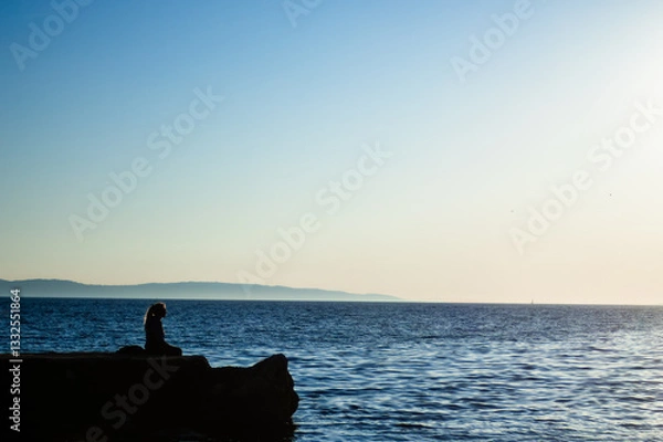 Fototapeta Wide image of a silhouette of a woman looking at the sea. Relax and inner harmony concept. Concept of relaxation and tranquility. Inner peace. Wallpaper for travel promotions .Space for text