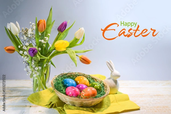 Obraz Colorful Easter eggs in a basket, spring bouquet with tulips and a small bunny, text Happy Easter, light blue gray background, copy space, selected focus