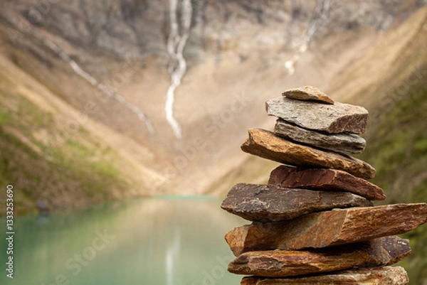 Obraz  Stone cairn in a nature scene with mountains and waterfall. Feeling of peace, balance and spirituality.