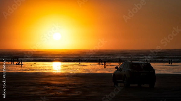 Fototapeta A breathtaking sunset casts golden hues over a serene beach, while silhouettes of people enjoy the tranquil setting, evoking feelings of relaxation and joy.
