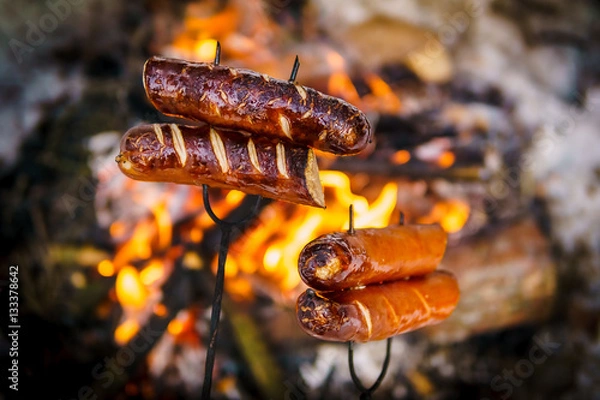 Obraz delicious sausages baked on a campfire in the forest