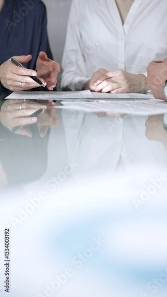Fototapeta Business people are reviewing contract terms during a meeting, negotiating and making decisions together, vertical close up view. Copy space area