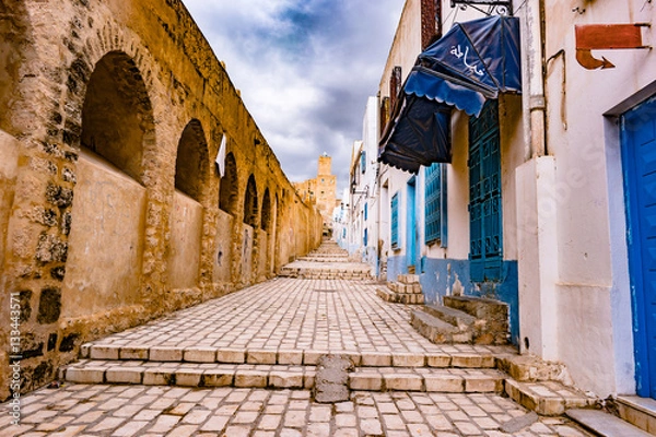 Fototapeta A street in Medina in Sousse, Tunisia. Magical space of medieval town with colorful walls and stone pavement.