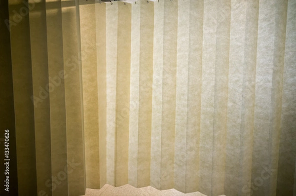 Fototapeta Hanging dividing curtain in a hospital ward. Folding room divider. Privacy curtain with multiple folds. Medical curtain hanging from a railing in a hospital room.